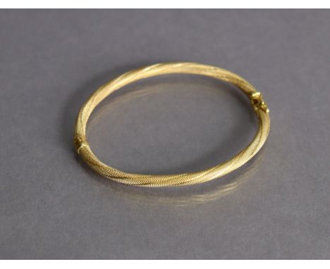 An 18ct yellow gold bangle with sprung hinge &amp; textured rope-twist design (7.5g).