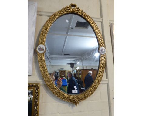 A Large Oval Gilt Framed Wall Mirror with Ceramic Mounts