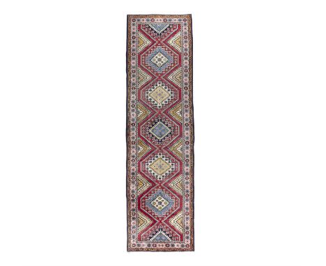 A WISS RUNNER, N.W IRAN. 400 x 110CMthe central field woven with seven diamond shaped medallions, in red, blue, navy and crea
