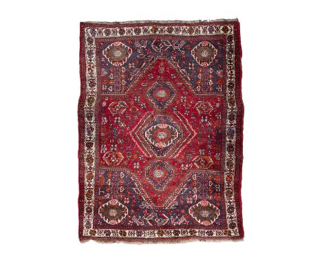 AN OLD PERSIAN SHIRAZ WOOL RUG. 241 x 167CMwoven in red, navy and cream tones, the large centre field with a star shaped meda