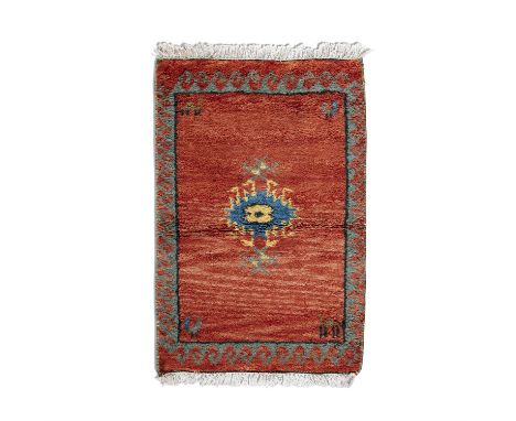 A TURKISH RUST GROUND RECTANGULAR RUG 64 X 98CM the large open field woven with a central hooked medallion and set with anima