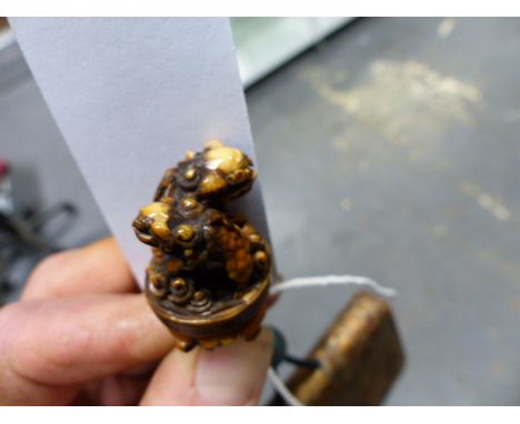 A JAPANESE PATINATED AND TOOLED PURSE WITH STAINED IVORY FOO LION NETSUKE AND A CLOISONNE DRAW BEAD.