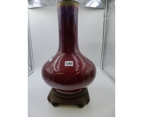 A CHINESE SANG DE BOEUF GLAZE LARGE BOTLE FORM VASE MOUNTED AS A LAMP ON CARVED HARDWOOD BASE.   OVERALL H.53cms.