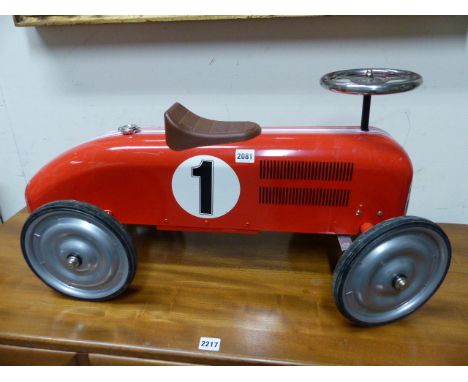 A VINTAGE CHILD'S TIN PLATE SIT ON MODEL RACING CAR.
