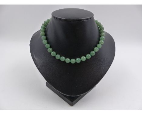 A UNIFORM STRING OF KNOTTED GREEN JADE BEADS APPROXIMATELY 7.5mm, APPROXIMATE WEIGHT 32.2grms.
