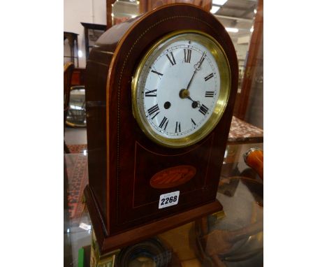 AN EDWARDIAN INLAID MAHOGANY ARCH FORM MANTLE CLOCK WITH BRASS BRACKET FEET.