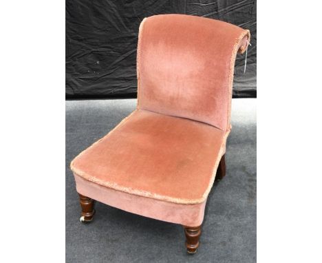 A Victorian walnut framed, salmon pink upholstered nursing chair, with rolled back, overstuffed seat, on turned forelegs and 