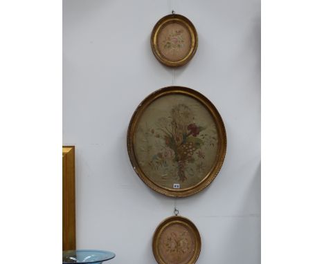 A Regency oval silkwork panel of a floral bouquet together with two others all in gilt frames