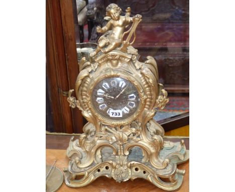 An antique cast brass case mantle clock with french striking movement, the case surmounted with cherub
