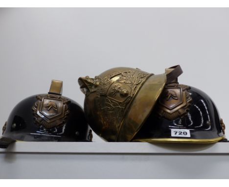An Antique French brass fire helmet together with two later German examples