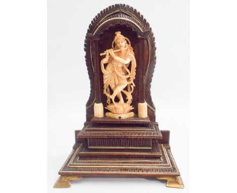 Early 20th century carved Indian ivory figure of a pipe playing deity within a carved hardwood ivory inlaid shrine standing o