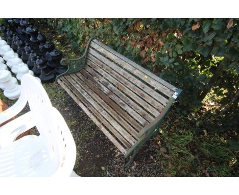 A two seater garden bench with wooden slats and green painted cast iron bench ends 