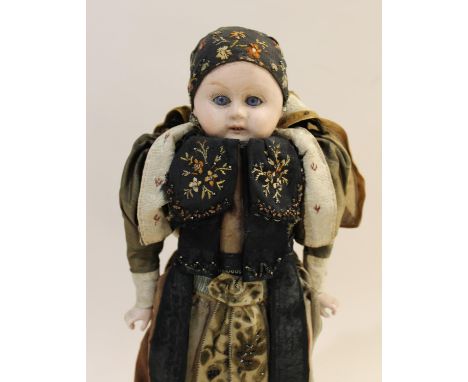 A bisque head doll with fixed blue glass eyes and open mouth (ears damaged), with bisque hands and a European costume (41cms 