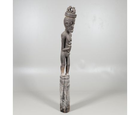 A large and unusual carved tribal figure, the standing figure holding an animal, with a head dress with further animals to th