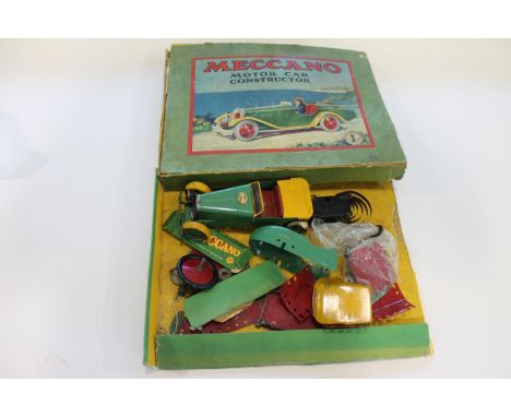 An assembled Meccano saloon car, with various other car parts and accessories. With its original box.  *CR:  The car, tyres a