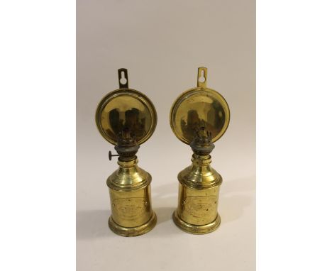 An unusual pair of brass parafin lamps, with a strut supporting a circular brass disc or reflector behind the light fitting. 