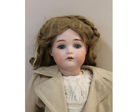 A bisque head doll with fixed blue eyes, open mouth and pierced ears. With a walking mechanism which moves the head from side