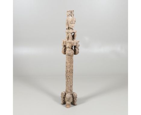 A carved crouched figure seated on a column, with a head dress and earings and supported on four feet. 126cms high.  *CR:  Se