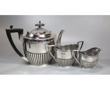 Edward VII silver fluted three piece service, the teapot with geometric ebonised handle, to include: teapot, two handled sucr