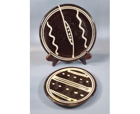 Michael Cardew, two similar pottery slipware plates in brown and cream. Impressed marks to the underside. 19 and 24cm diamete