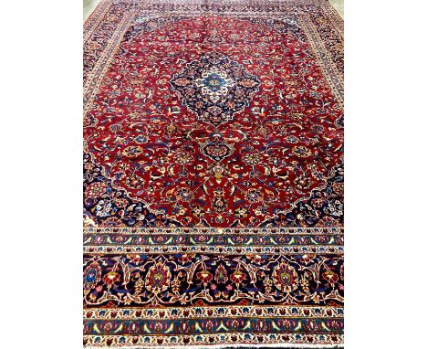 Large fine hand woven Iranian carpet on a red and navy ground with large central medallion.  Kashan region of Iran.   393x284