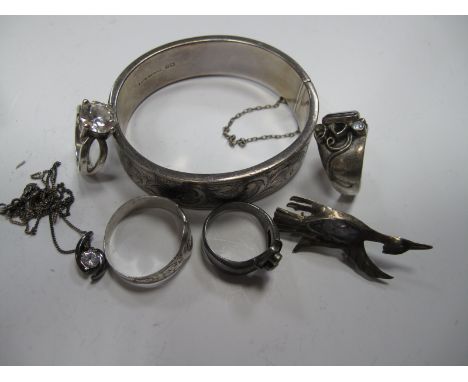 A Hallmarked Silver Hinged Bangle, with engraved foliate panel to integral snap clasp and safety chain, four rings of various