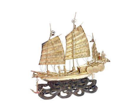 CHINESE WHITE METAL MODEL OF A JUNK, on a carved wood base formed as waves, 15cm long