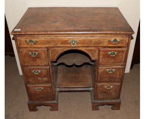 A George I Walnut and Feather Banded Kneehole Dressing Table, early 18th century, the quarter veneered top above a long friez