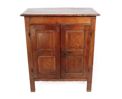 ^ An 18th Century Joined Oak Cupboard, the boarded top above two cupboard doors with four fielded panels enclosing a shelf, o