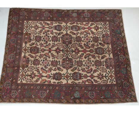 Indian Carpet, circa 1920 The pale camel field with an allover design of large flowerheads, palmettes and serrated leaves enc