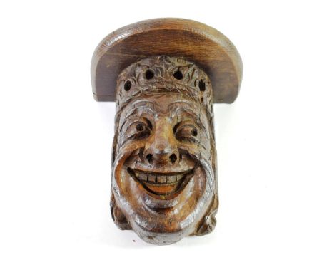 A Carved Oak Bracket, in 16th century style, as a crowned smiling head, 25cm high; with later shelf