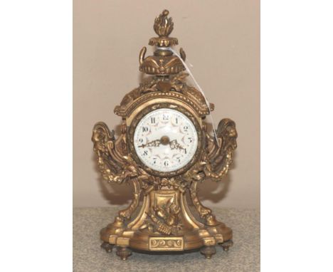 An Ormolu Mantel Timepiece, circa 1900, urn shaped finial, side rams head masks and swag decoration, enamel dial with Arabic 