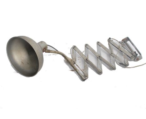A vintage french polished steel lamp being wall mounted attached to an extending scissor action arm.