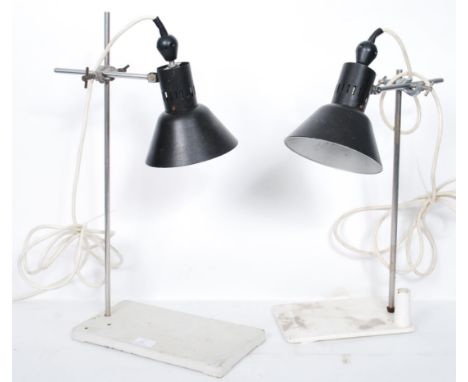 A pair of vintage retro 20th century industrial desk lamps having black enamel pendant shades mounted on adjustable clamp sta