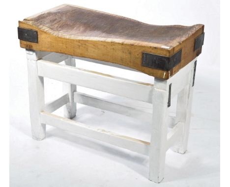 A vintage mid century heavy beech wood butchers block with metal bracket ends and of parquetry design being raised on a paint