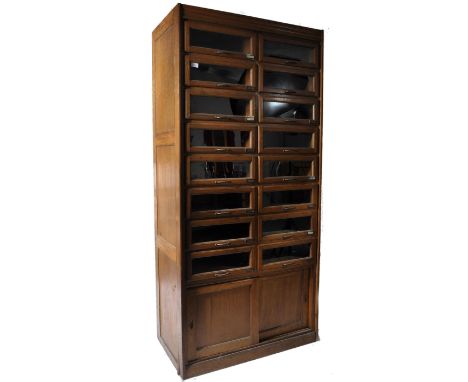 An early 20th century light oak shop display haberdashery retailers shirt cabinet, fitted with sixteen up and over glazed pan