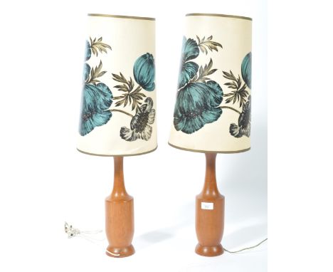 A pair of retro mid 20th century turned teak wood table lamps, each lamp with matching retro floral shades. Measures 75cm tal