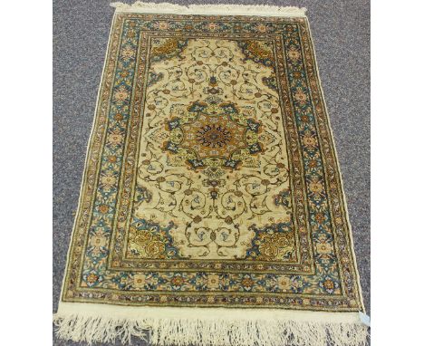 A Kashmir part silk rug, late 20th century, the ivory field with a flowerhead medallion, within a green palmette border, 114c