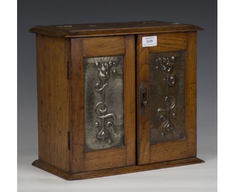 An Edwardian oak smoker's cabinet with inset pressed copper door panels, height 31cm, width 34cm, depth 17cm.Buyer’s Premium 