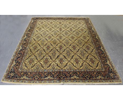 An Indian carpet, mid/late 20th century, the ivory field with an overall floral lattice, within a midnight blue border, 362cm