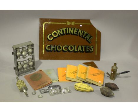 A group of chocolate making items, including moulds, presses and instruction books, and a glass advertising sign (fault).Buye