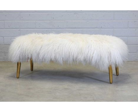 A 'Mongolian' bench, by Jonathan Adler, with a long-haired sheepskin seat, raised on brass supports,112cm wide 46cm deep43cm 