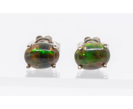 A pair of silver and black Ethiopian opal stud earrings, claw set with oval cabochon opals, approx. 7 x 5mm, post and scroll 