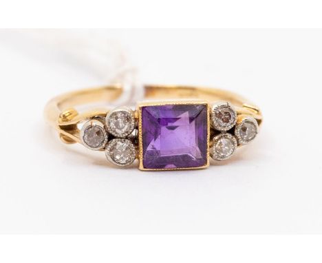 A Edwardian amethyst and diamond 18ct gold dress ring, comprising a central square cut amethyst with milled border, set eithe