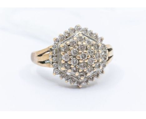 A diamond and yellow metal cluster ring, comprising a hexagonal setting of claw set round brilliant cut diamonds, setting app