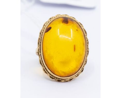 An amber and 9ct gold dress ring, oval amber within a decorative rope border, setting approx 20 x 28mm, size N, total gross w