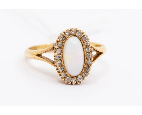 An Edwardian opal and diamond 18ct gold ring, comprising an elongated white opal within a border of small diamonds, setting a