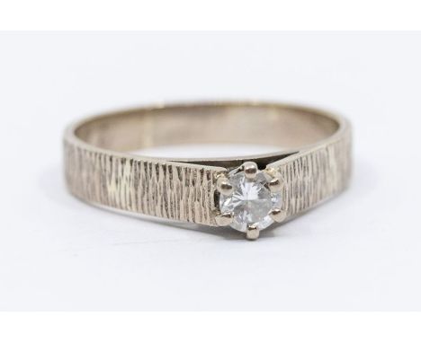 An 18ct white gold diamond solitaire ring, the brilliant cut stone of 0.25ct, rusticated shank, ring size R 1/2, 4.24 grams.