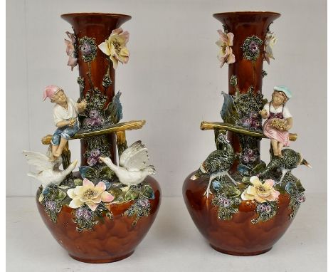 A pair of late 19th Century to early 20th Century shaft and globe vases, each vase applied with a boy and a girl feeding gees