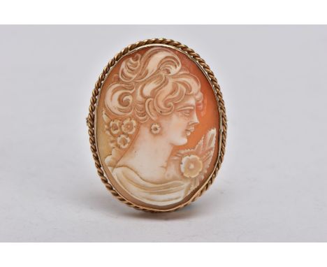 A YELLOW METAL CAMEO BROOCH, of an oval form, depicting a lady in profile, within a collet mount and a rope twist surround, f
